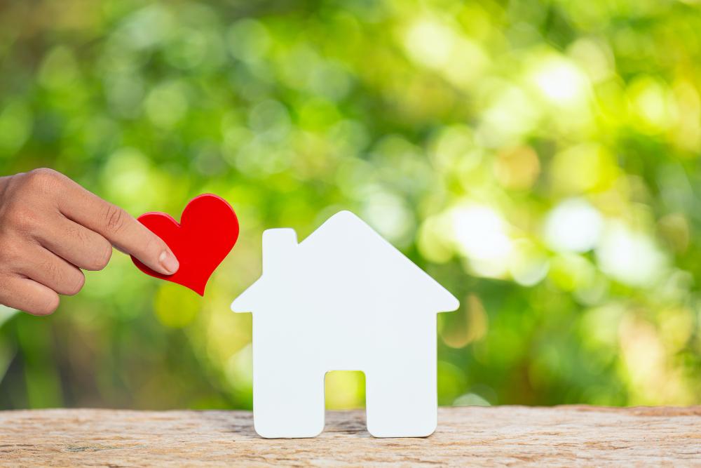 photo-d-une-maison-modele-et-main-tenant-un-coeur-en-papier